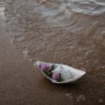 flowers in a paper boat on the beach