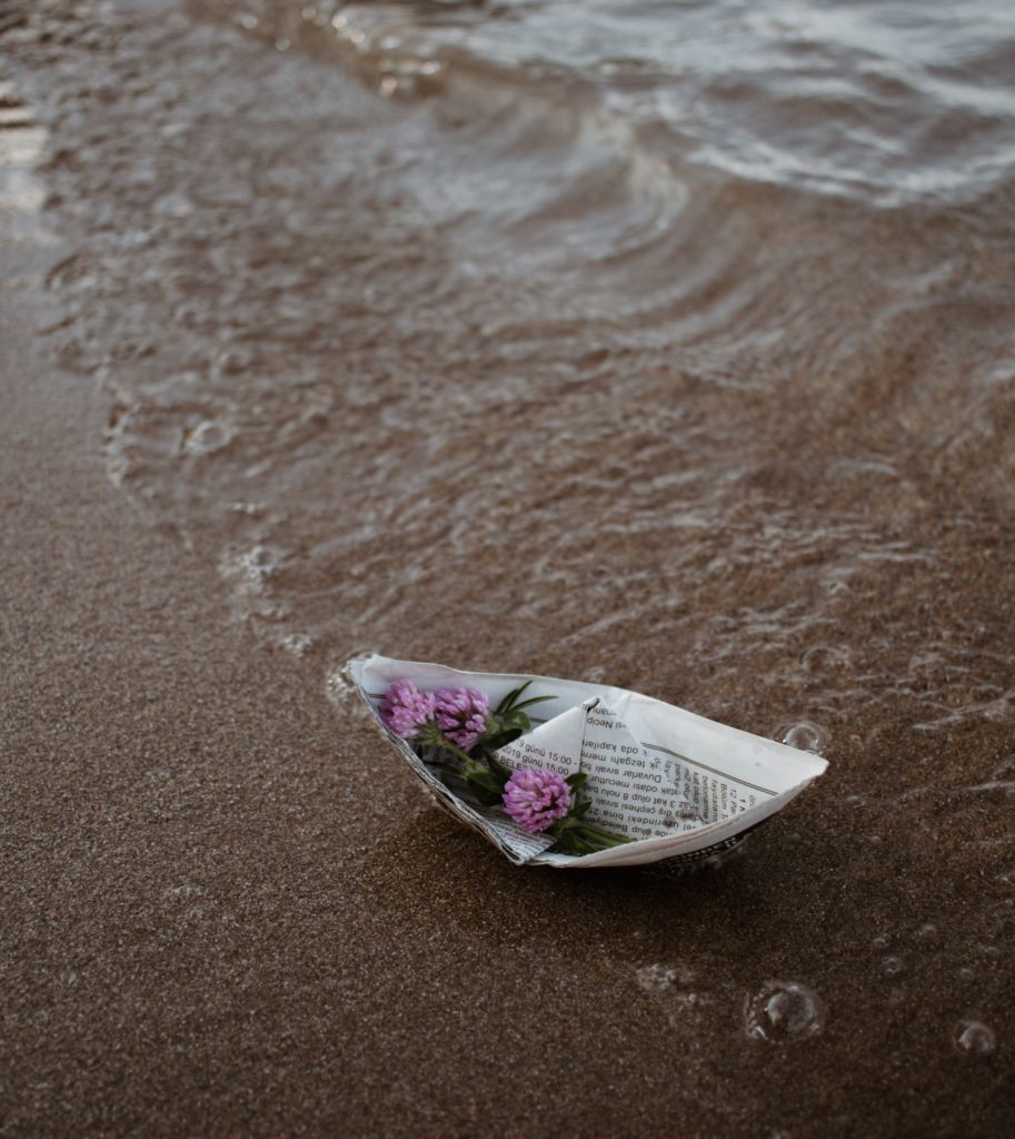 flowers in a paper boat on the beach